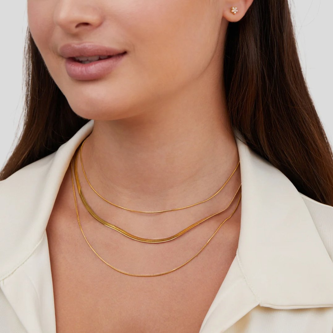 Gold Multi-Layered Chain Necklace, worn layered at the neck over a cream collar, three gold chains