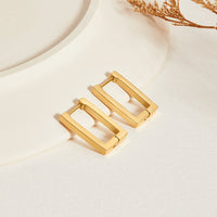 Gold Rectangle Hoop Earrings, pair of rectangular gold hoops on cream stone, dried stem nearby