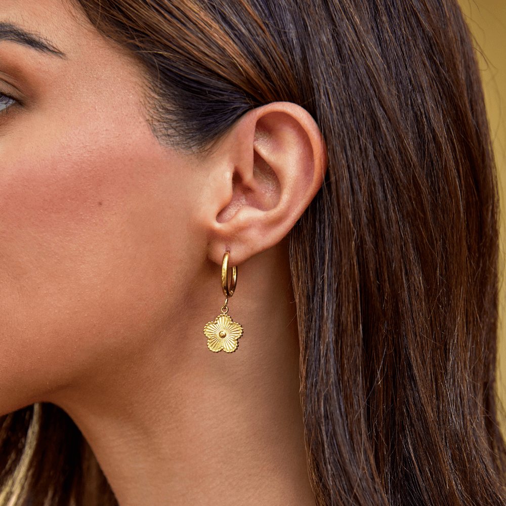 Golden Clover Hoop Earrings, worn on an ear with a gold hoop and flower charm