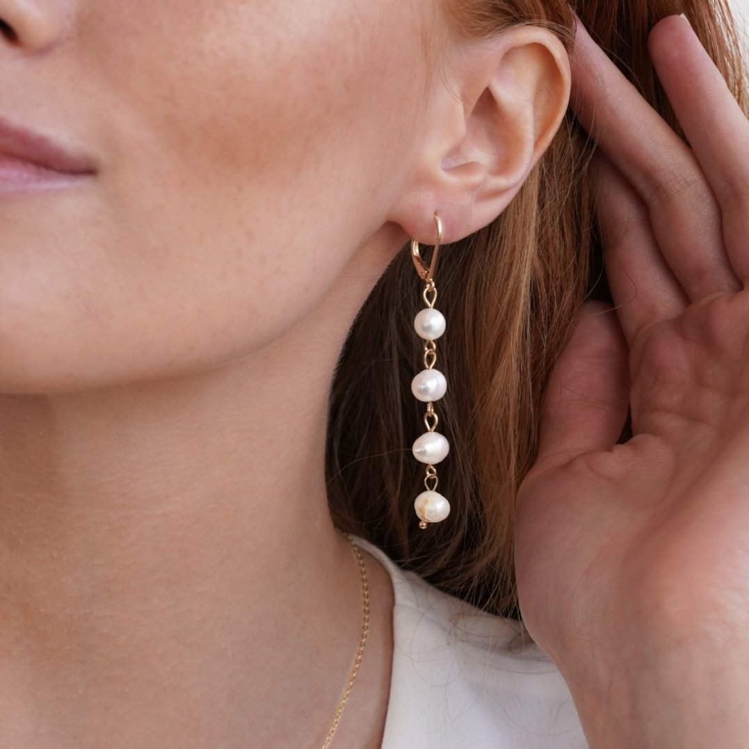Golden Freshwater Pearl Earrings, worn on an ear with a hand cupped beside it, four pearls