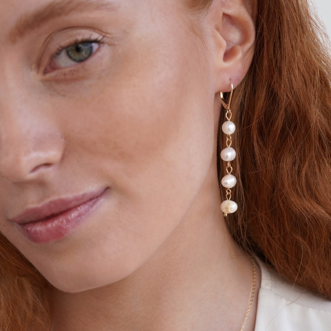 Golden Freshwater Pearl Earrings, worn on an ear, four pearls on a gold drop