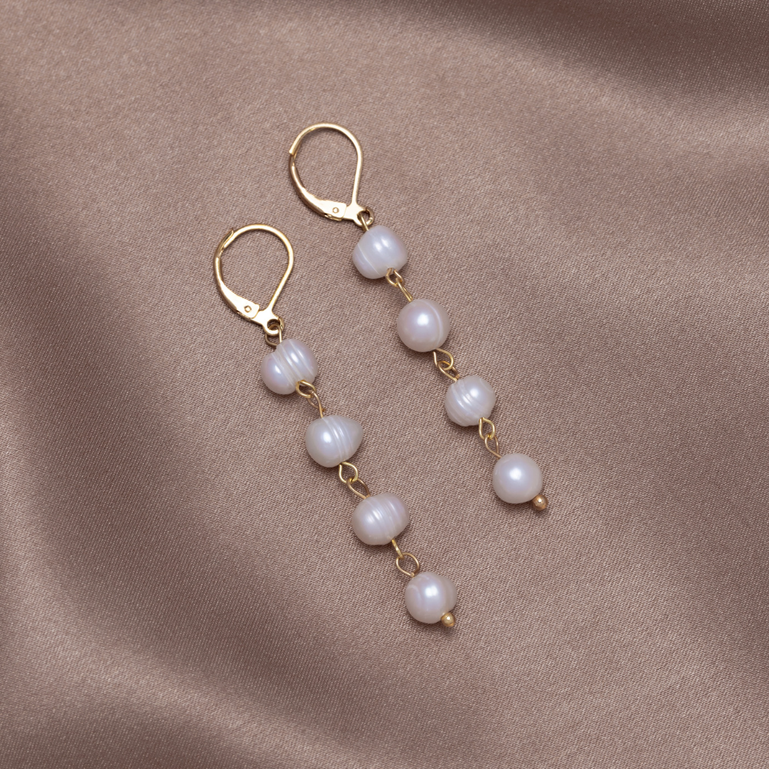 Golden Freshwater Pearl Earrings, pair of drop earrings laid on satin, gold hooks and pearls