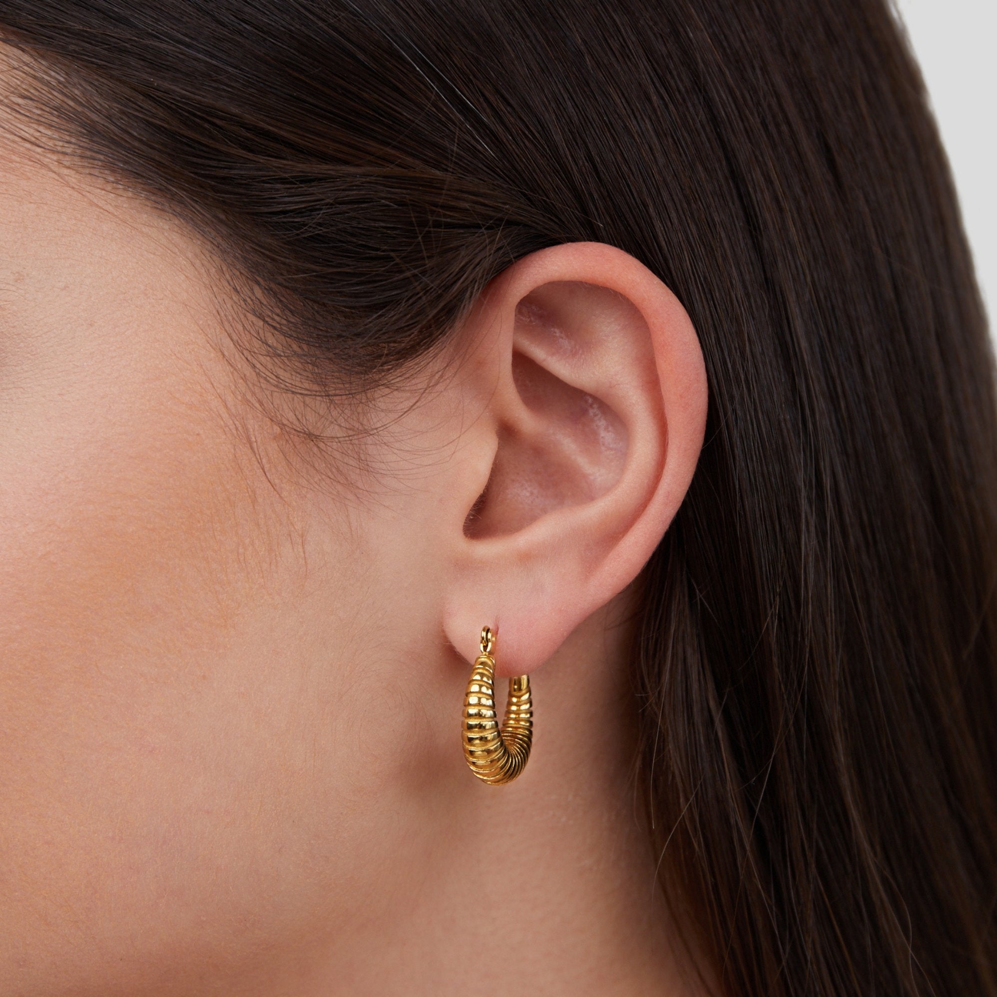 Golden Mia Croissant Hoop Earrings, worn on an ear, close-up with ribbed gold hoop