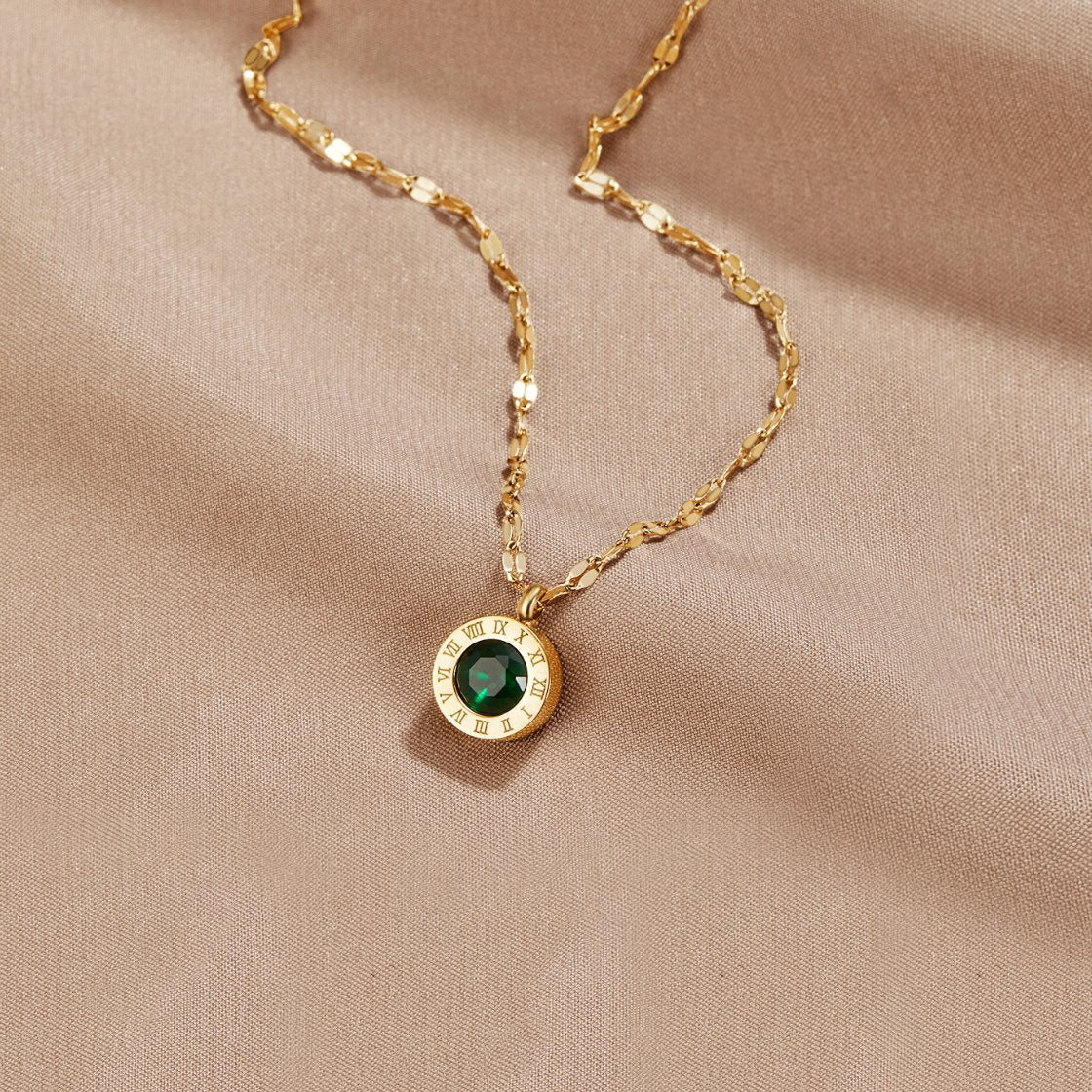 Green Crystal Athena Necklace, laid flat on beige satin, gold chain with green pendant