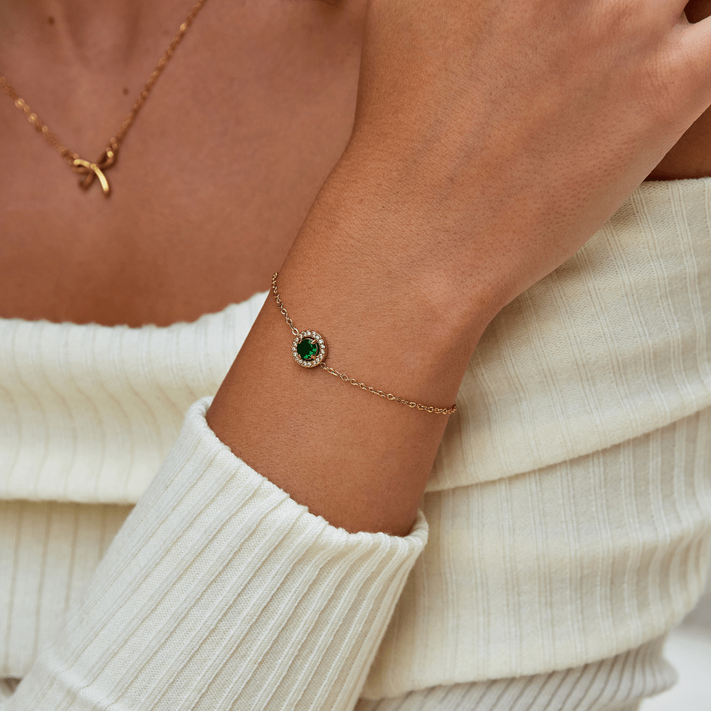 Green Emerald Crystal Bracelet, worn on a wrist with a cream knit sweater and gold necklace