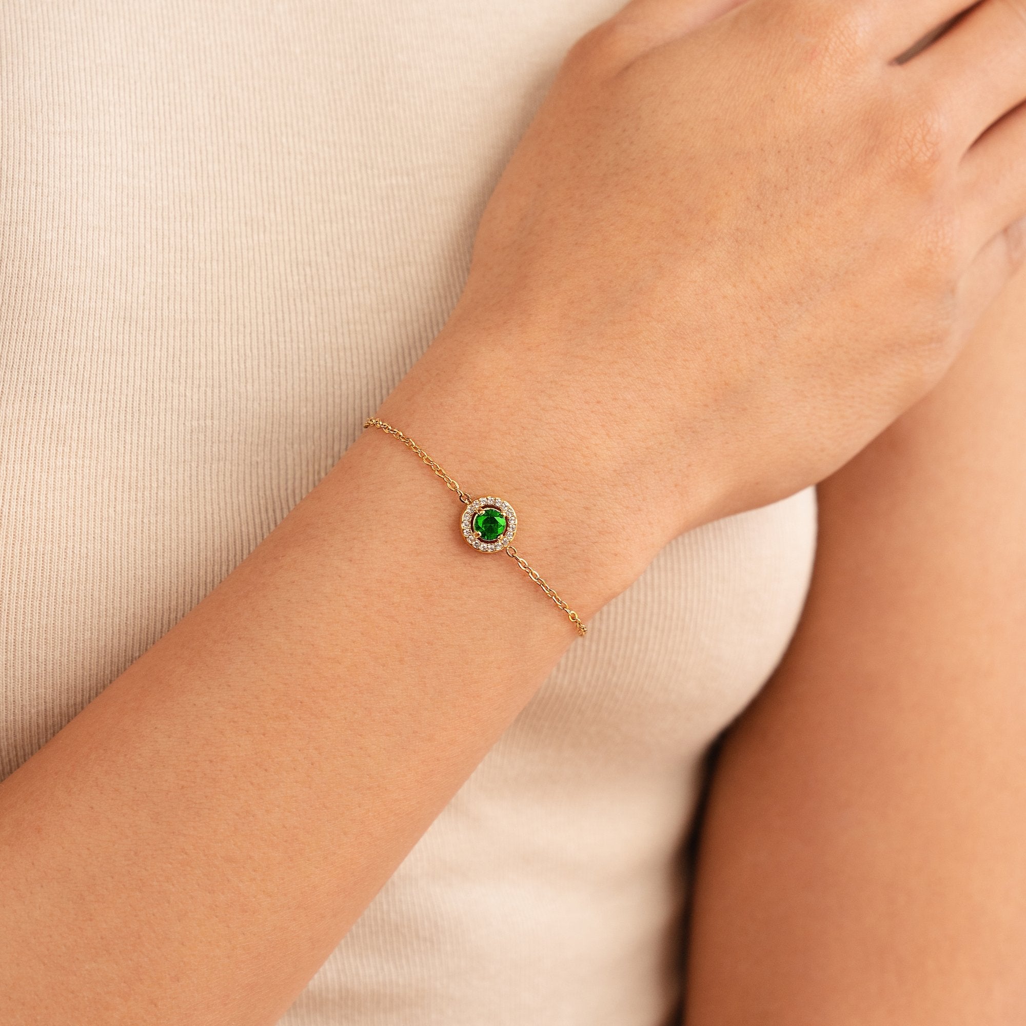 Green Emerald Crystal Bracelet, worn on a wrist over a cream top, green stone with halo