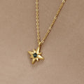 Guiding Star Emerald Crystal Necklace, worn on a beige fabric backdrop, gold chain with star