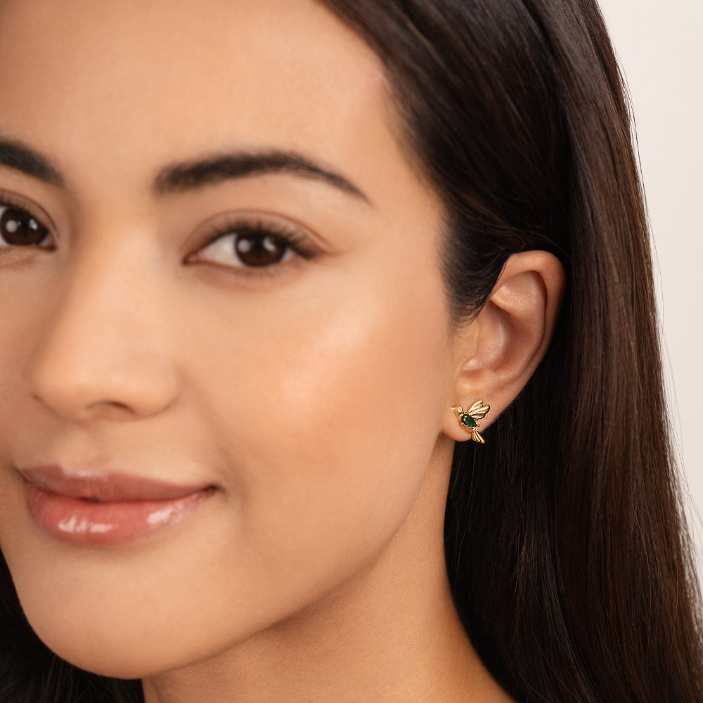 Hummingbird Stud Earrings, worn in one ear, gold wings with a small green stone