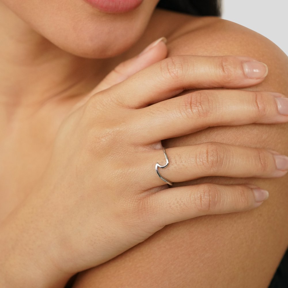 Imari Silver Wave Ring, worn on a hand resting on a bare shoulder, silver wave-shaped band