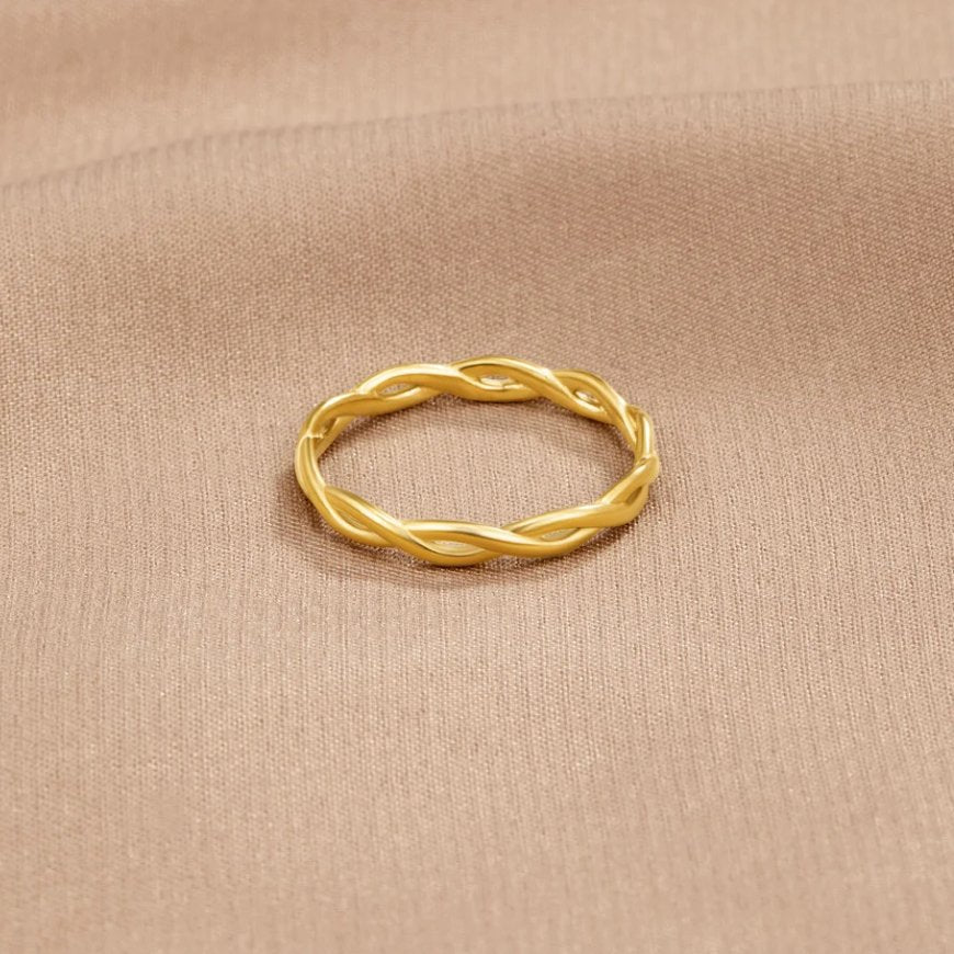 Infinity 18K Gold Twist Ring, lying flat on beige satin, twisted gold band seen from above