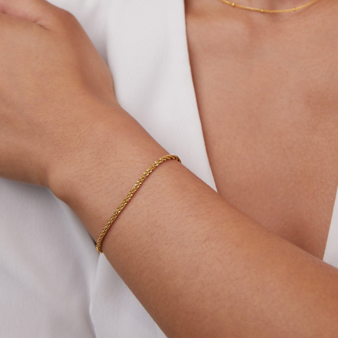 Kai 18K Gold Bracelet, worn on a wrist with a white top and fine gold necklace