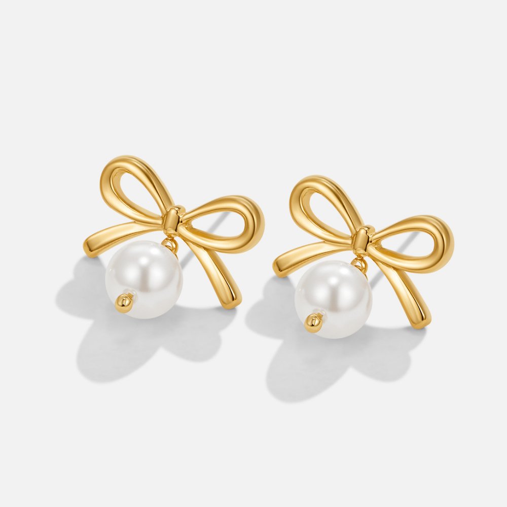 Laila Bow Pearl Earrings, pair of gold bow earrings with hanging white pearls on white background