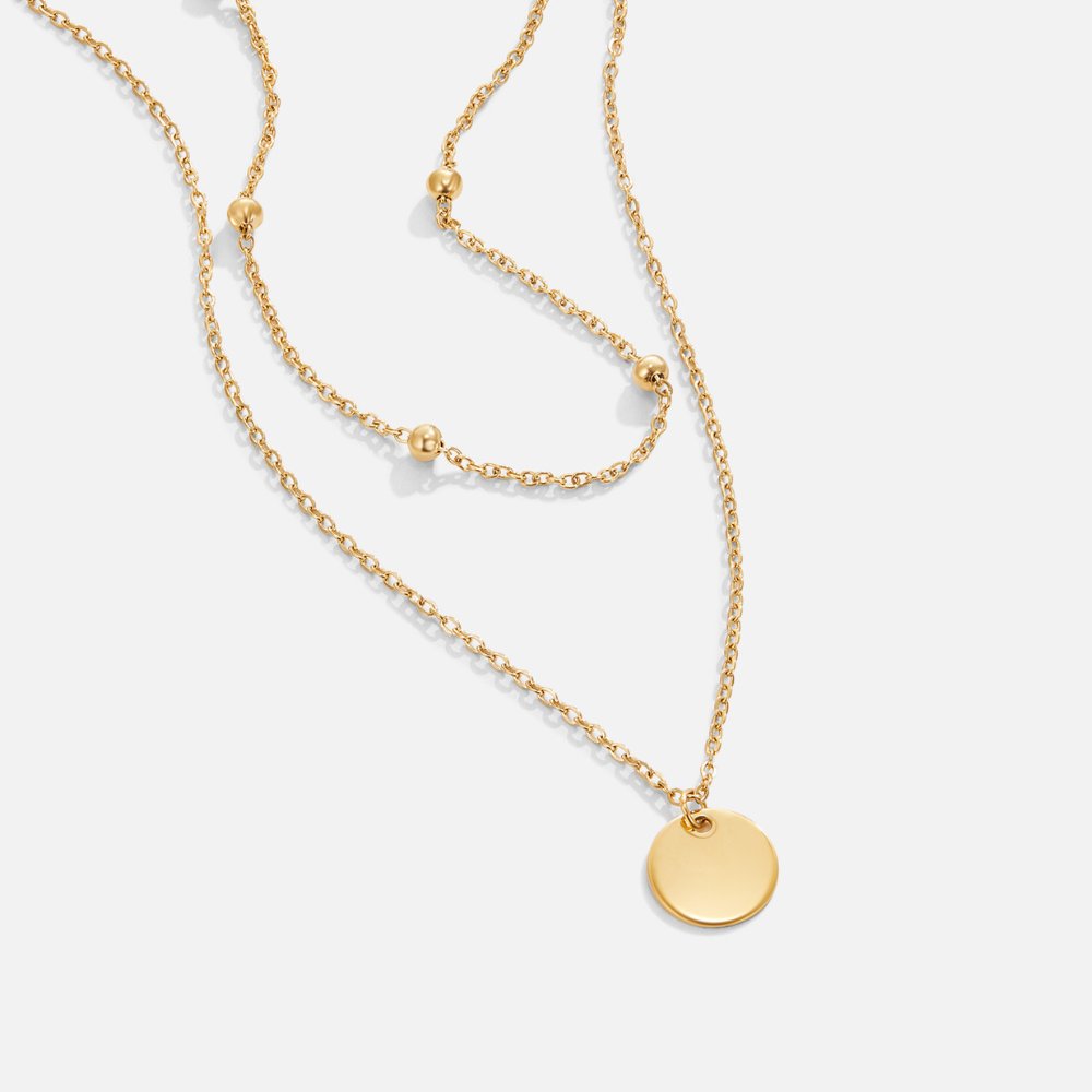 Layered Disc Necklace, laid flat on white, two gold chains with a round disc pendant