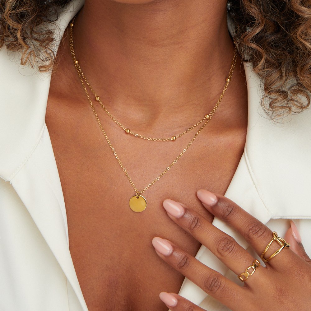 Layered Disc Necklace, worn on a neck with a white open-collar top, gold disc pendant