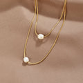 Layered Freshwater Pearl Necklace, two gold chains laid on satin, each with one pearl