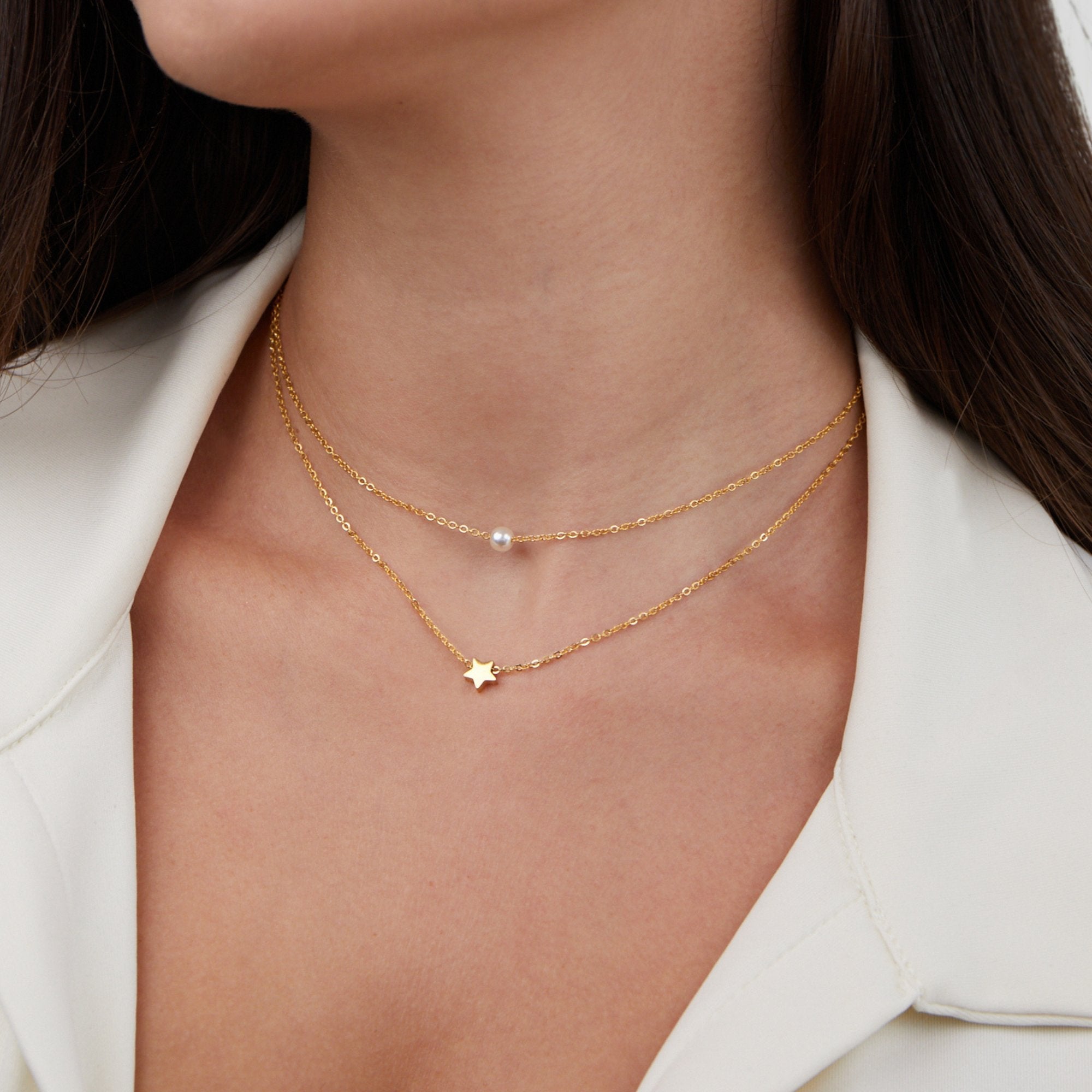 Layered Gold Star & Pearl Necklace, worn on a neck over a white collared top, layered chains