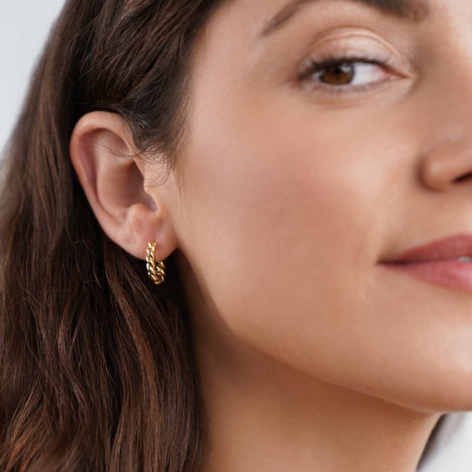 Layla Gold Twist Earrings, worn on an ear by a woman with long brown hair
