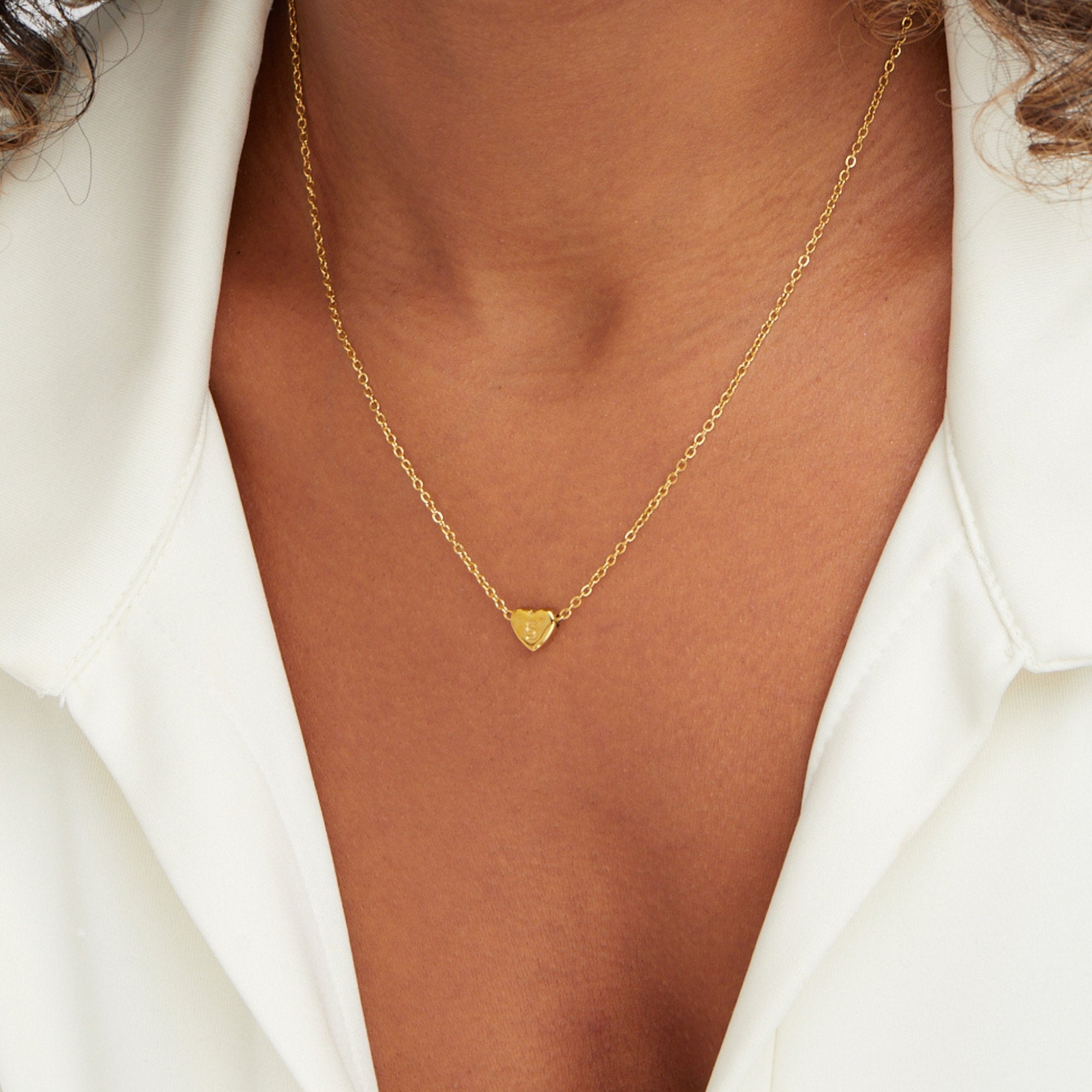 Letter Heart Necklace, worn at the neckline over a white open-collar shirt, gold heart pendant