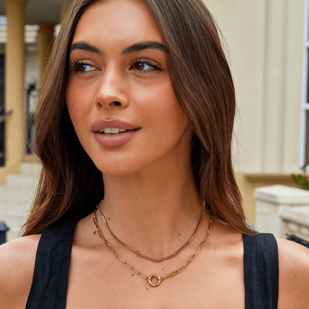 Cordelia Gold Crystal Necklace, worn as layered gold necklaces on a woman in a dark top