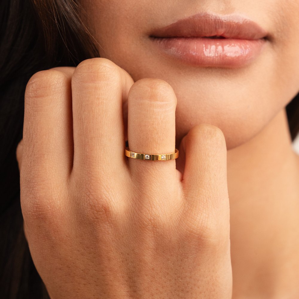 Lucia Crystal Ring, worn on a hand near a woman's chin, gold band with three small stones