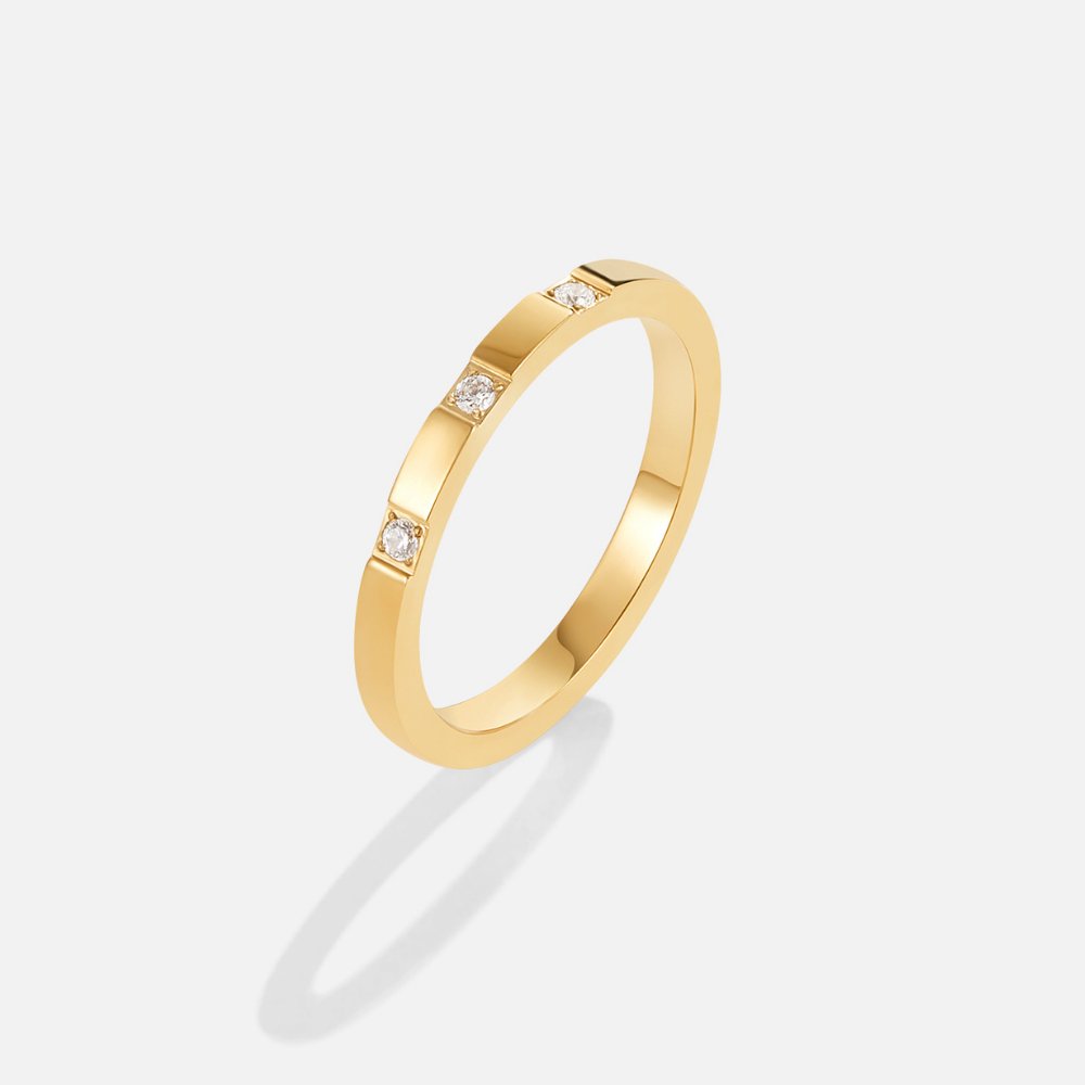 Lucia Crystal Ring, standing upright on a plain grey background, gold band with three small stones
