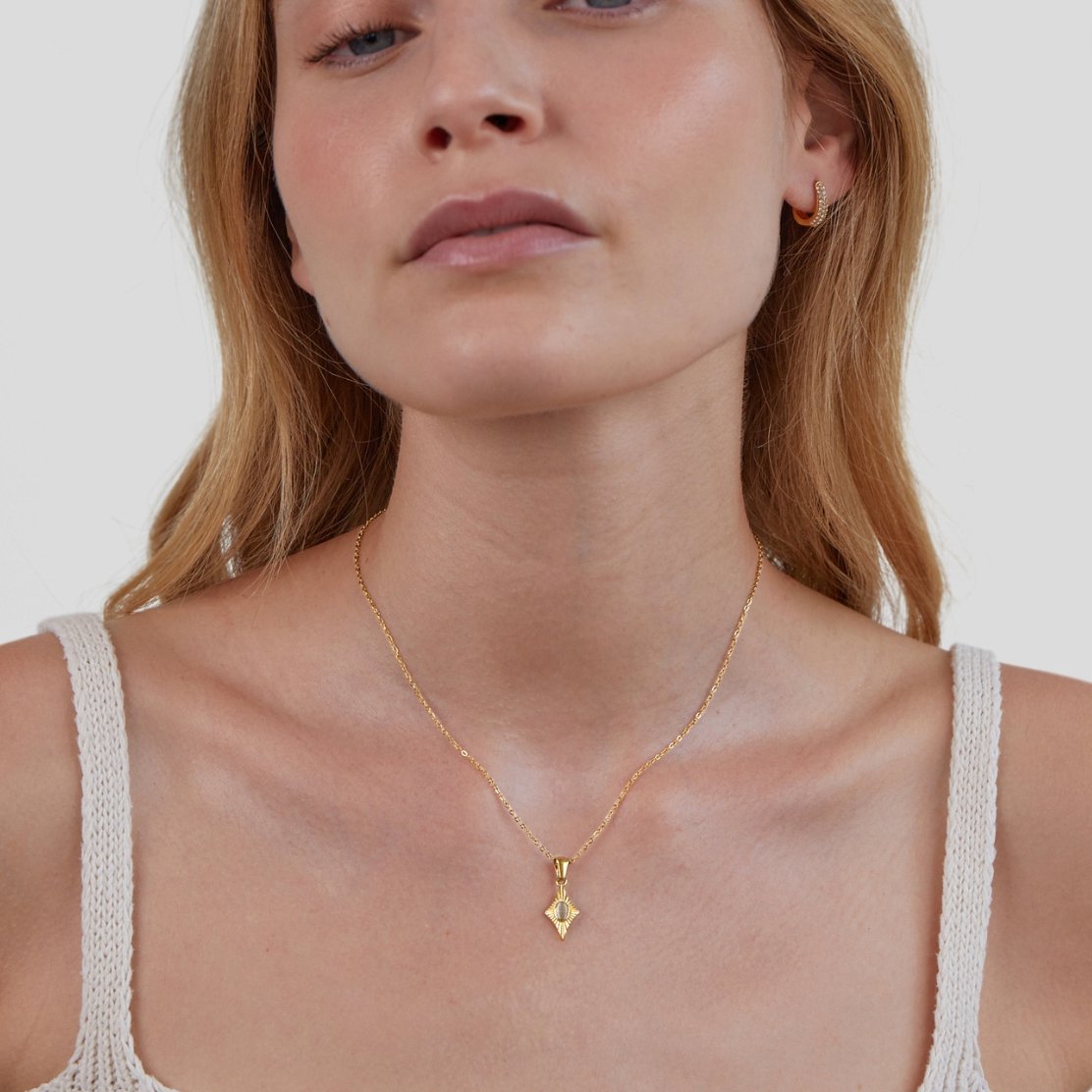 Luna White Opal Gold Necklace, worn on a model with a white knit top and gold hoop earring