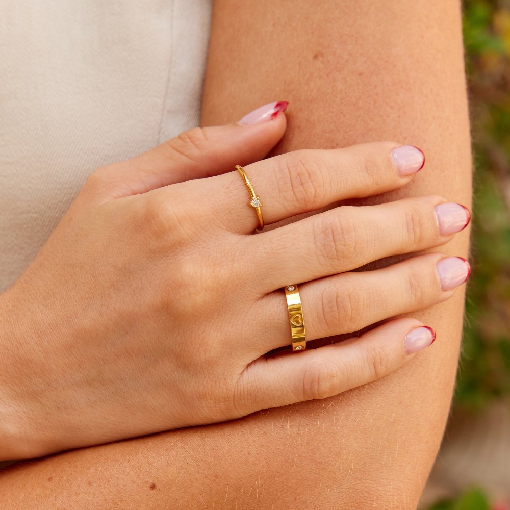 Mari Heart Gold Ring, worn on a hand with a thin gold ring set with a small stone