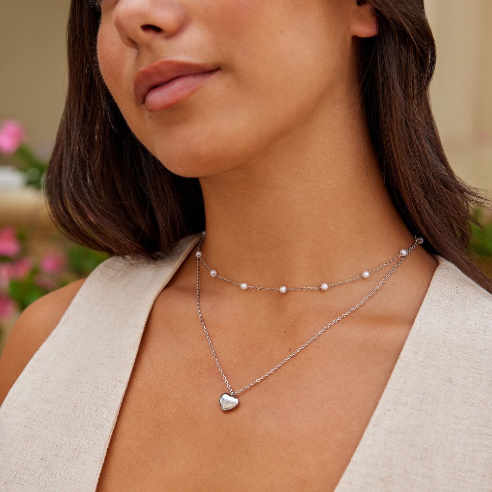 Marina Love Silver Necklace, worn on a model with two silver chains, pearl beads and a heart