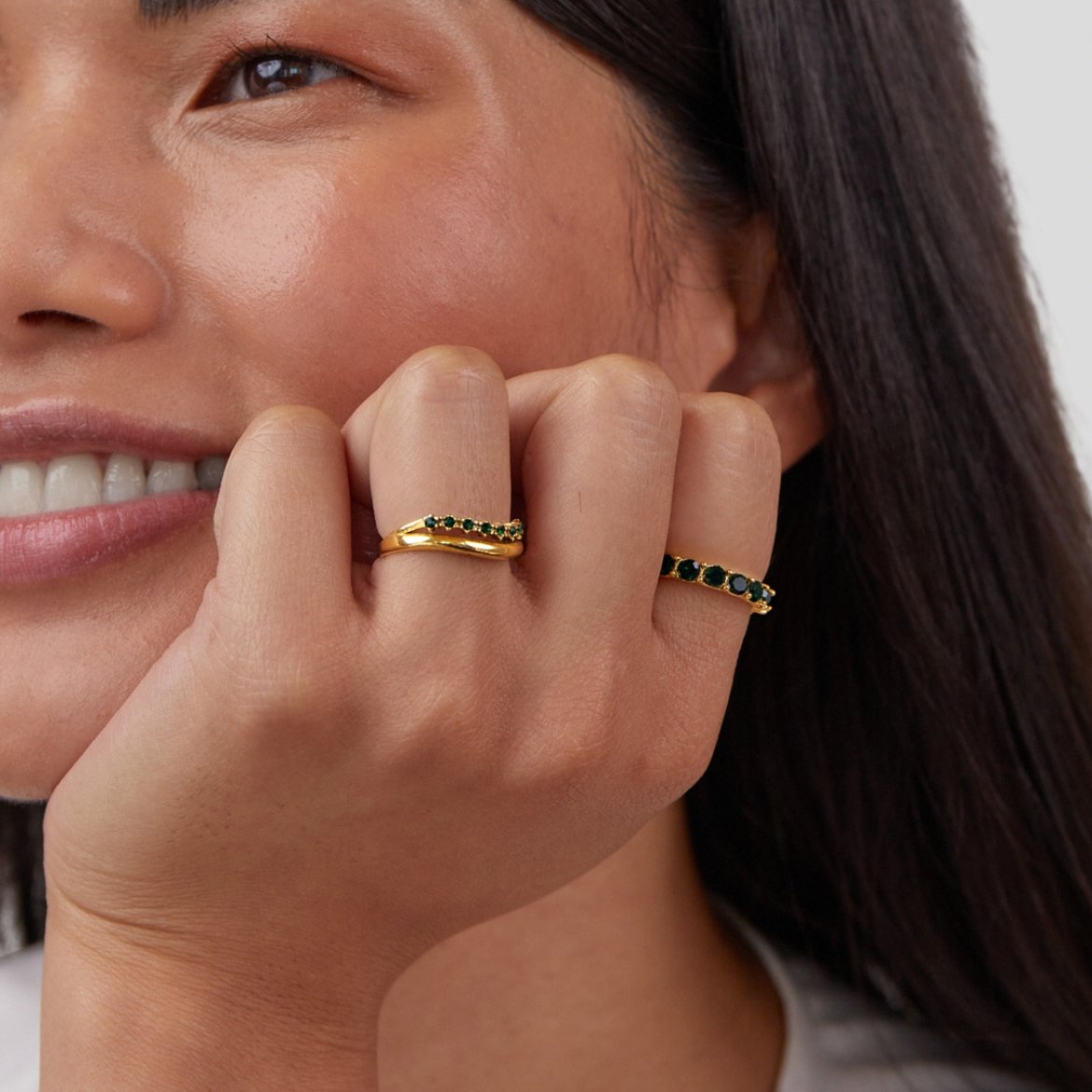 Marissa Emerald Green Layered Ring, worn on a hand against cheek, gold rings with green stones