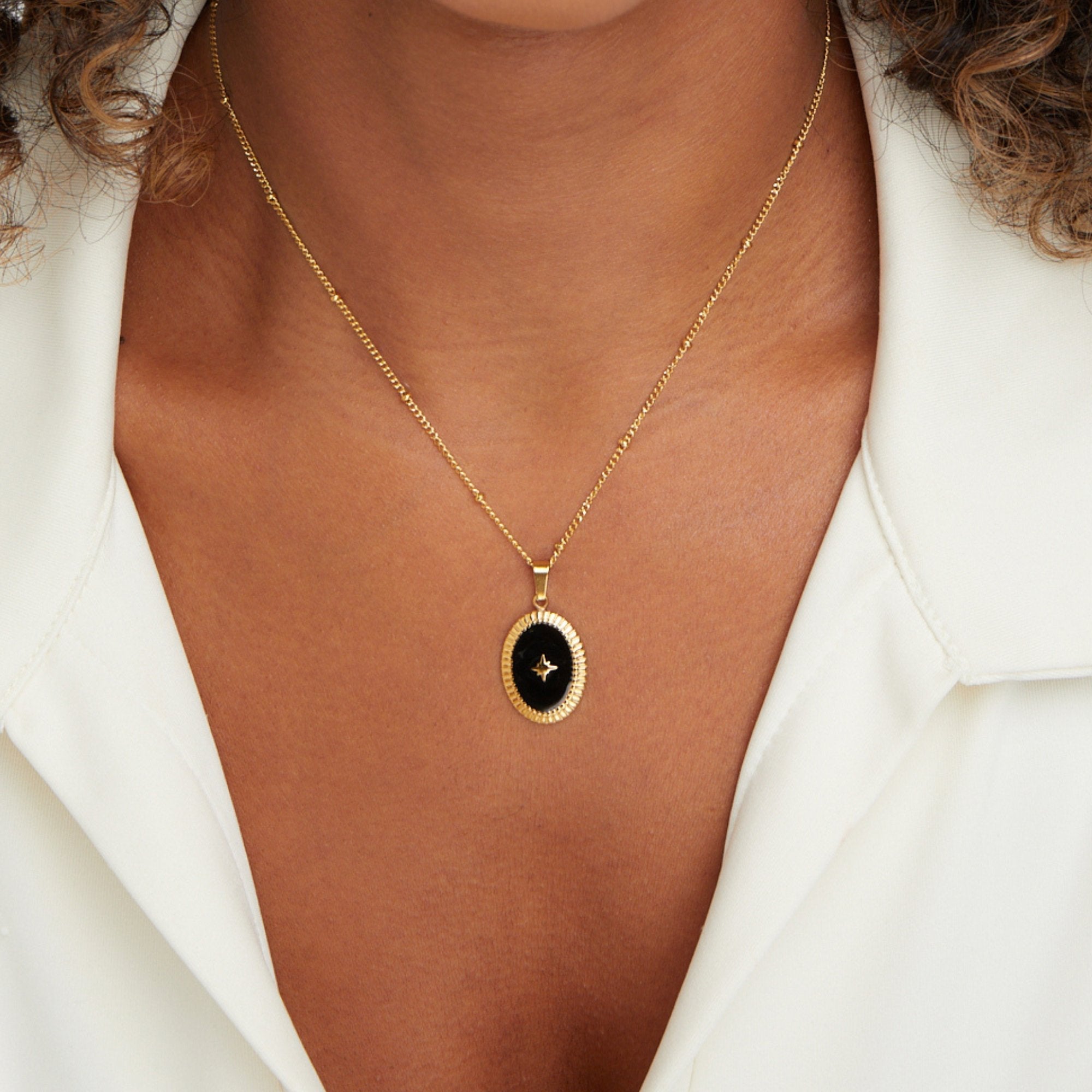 Midnight Star Onyx Necklace, worn on a neck over a white collared shirt, black oval pendant