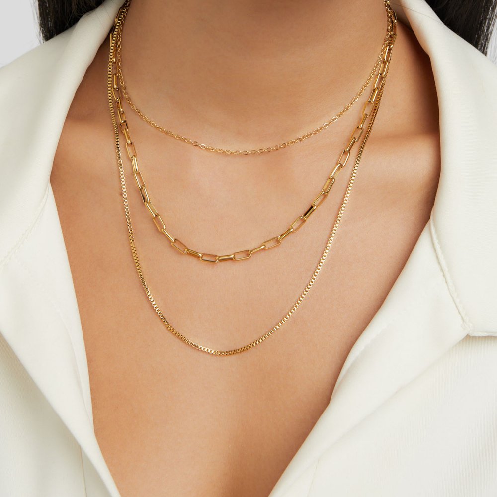 Miela Layered Chain Necklace, worn on a neck over a white collared top, three gold chains layered