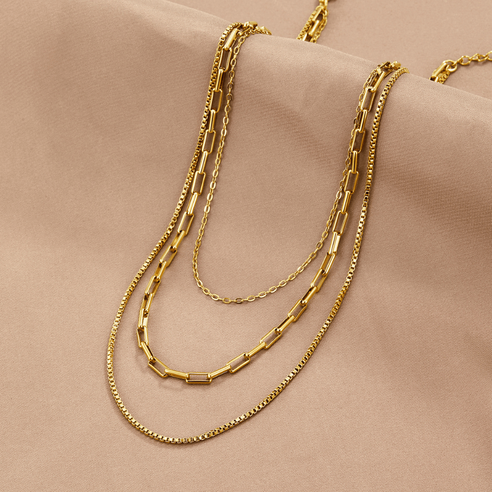 Miela Layered Chain Necklace, three gold chains layered on draped beige fabric