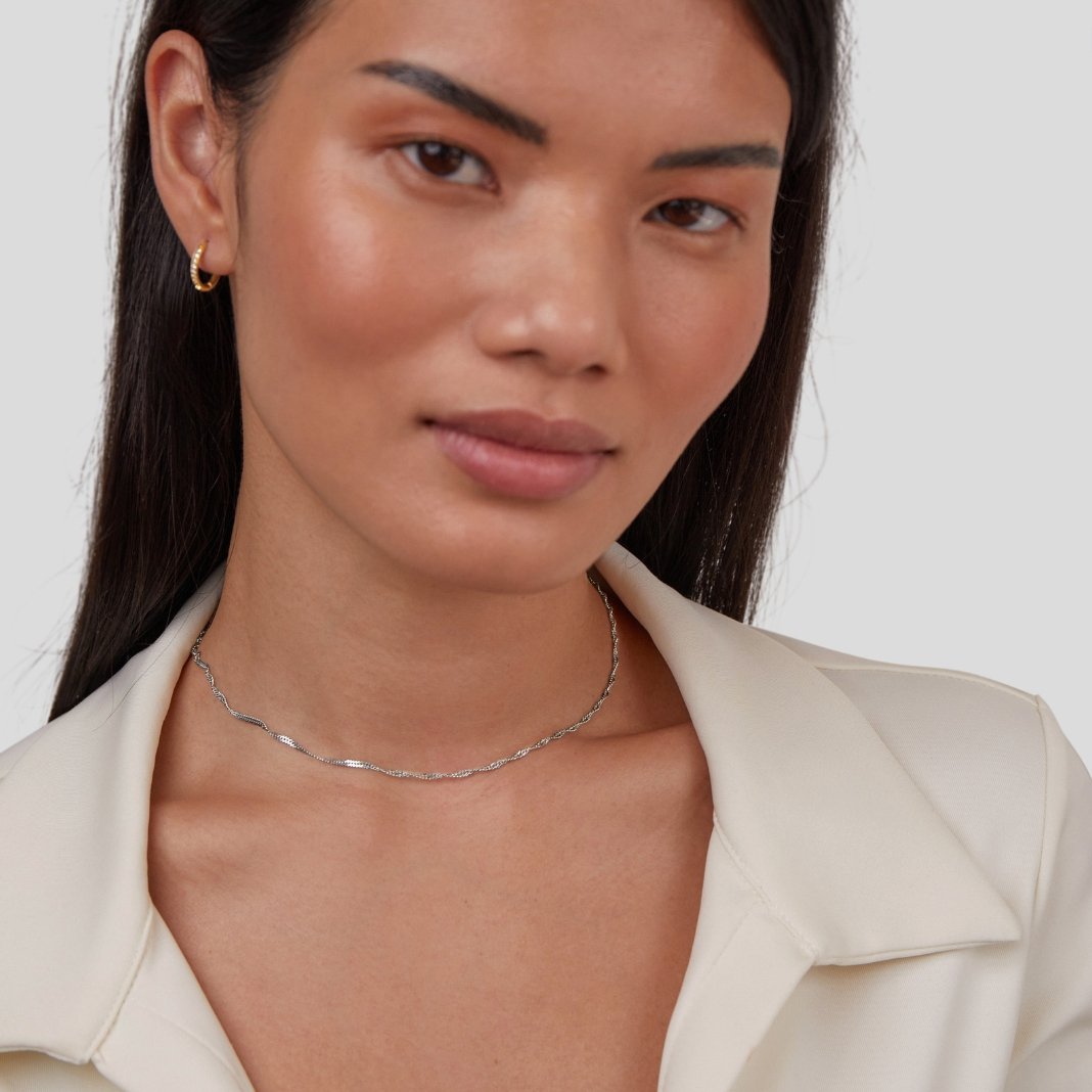 Mila Twist Silver Chain Necklace, worn on a model with a cream collared top and gold hoop earring