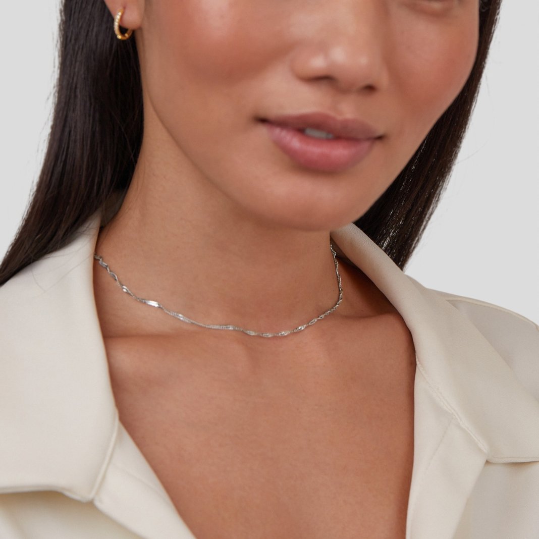Mila Twist Silver Chain Necklace, worn on a neck with a gold hoop earring and cream collar