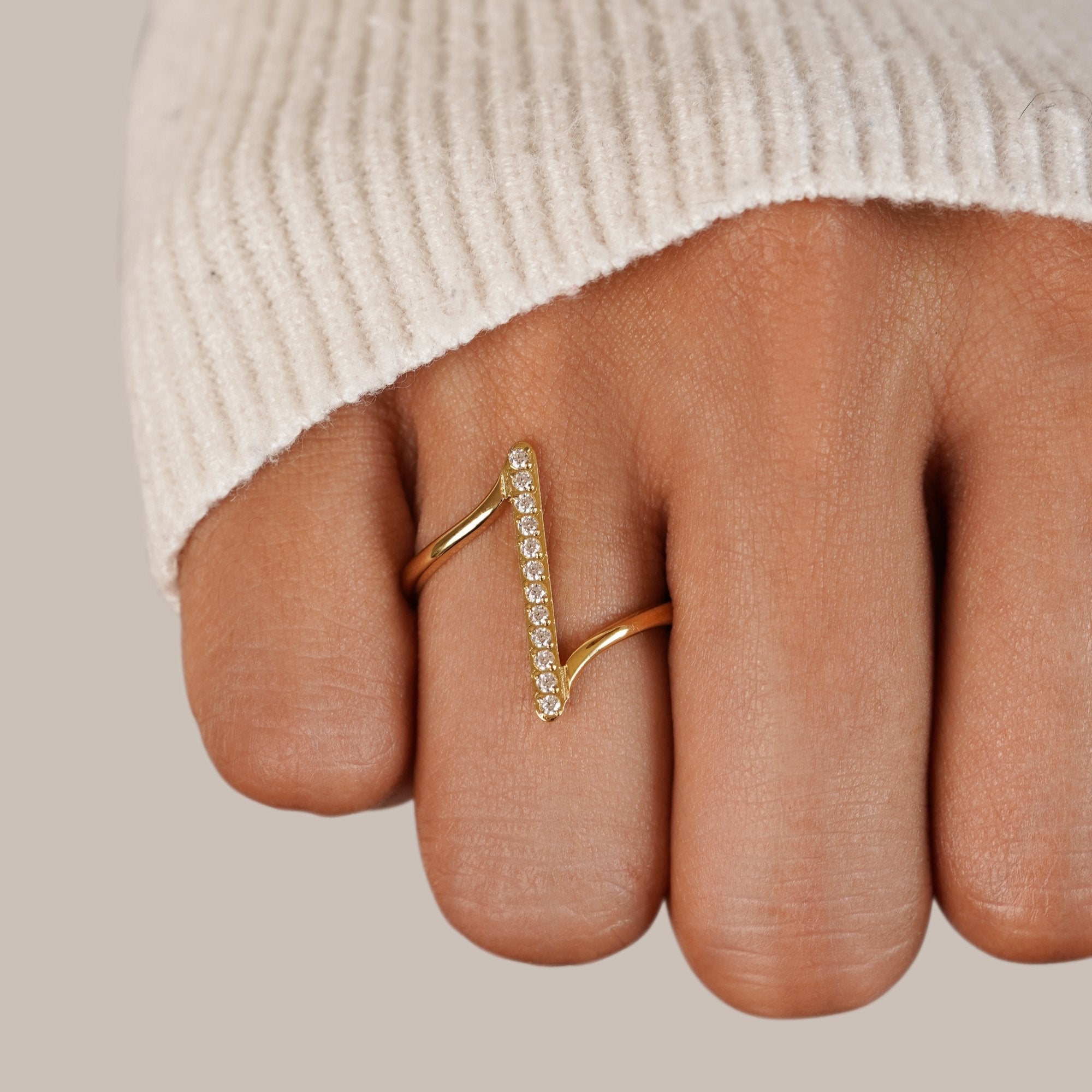 Mila Twisted Gold Ring, worn on a finger with a cream knit sleeve, gold with small stones