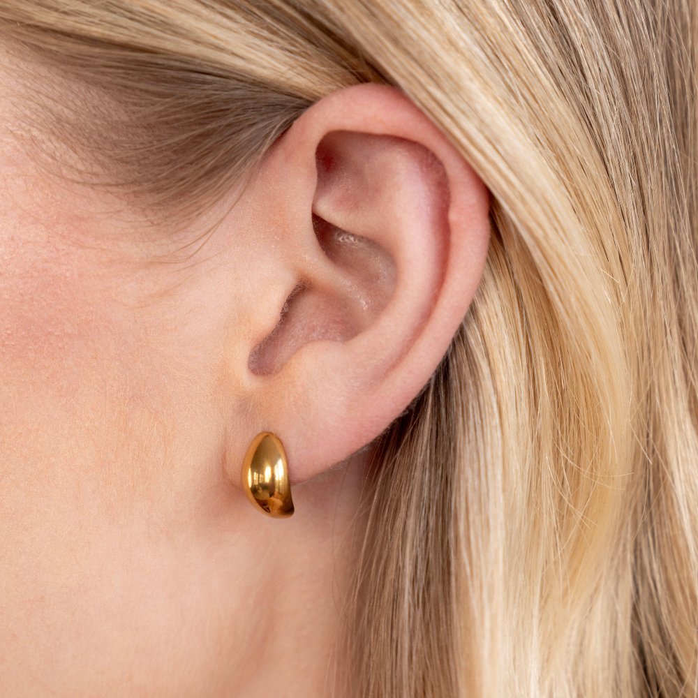 Mini Curve Earrings, worn on an ear, close-up of a polished gold dome earring
