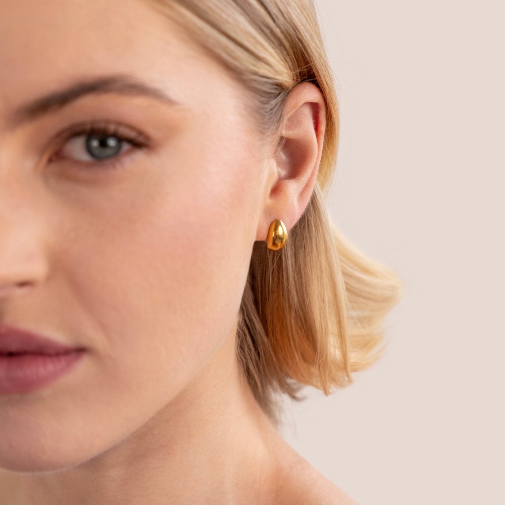 Mini Curve Earrings, worn on an ear, close-up on a woman with blonde bob hair