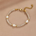 Moonstone & Pearl Bead Bracelet, laid flat on a beige fabric, grey beads with pearls and gold
