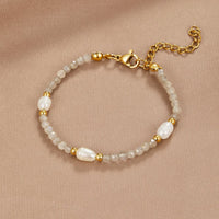 Moonstone & Pearl Bead Bracelet, laid flat on a beige fabric, grey beads with pearls and gold