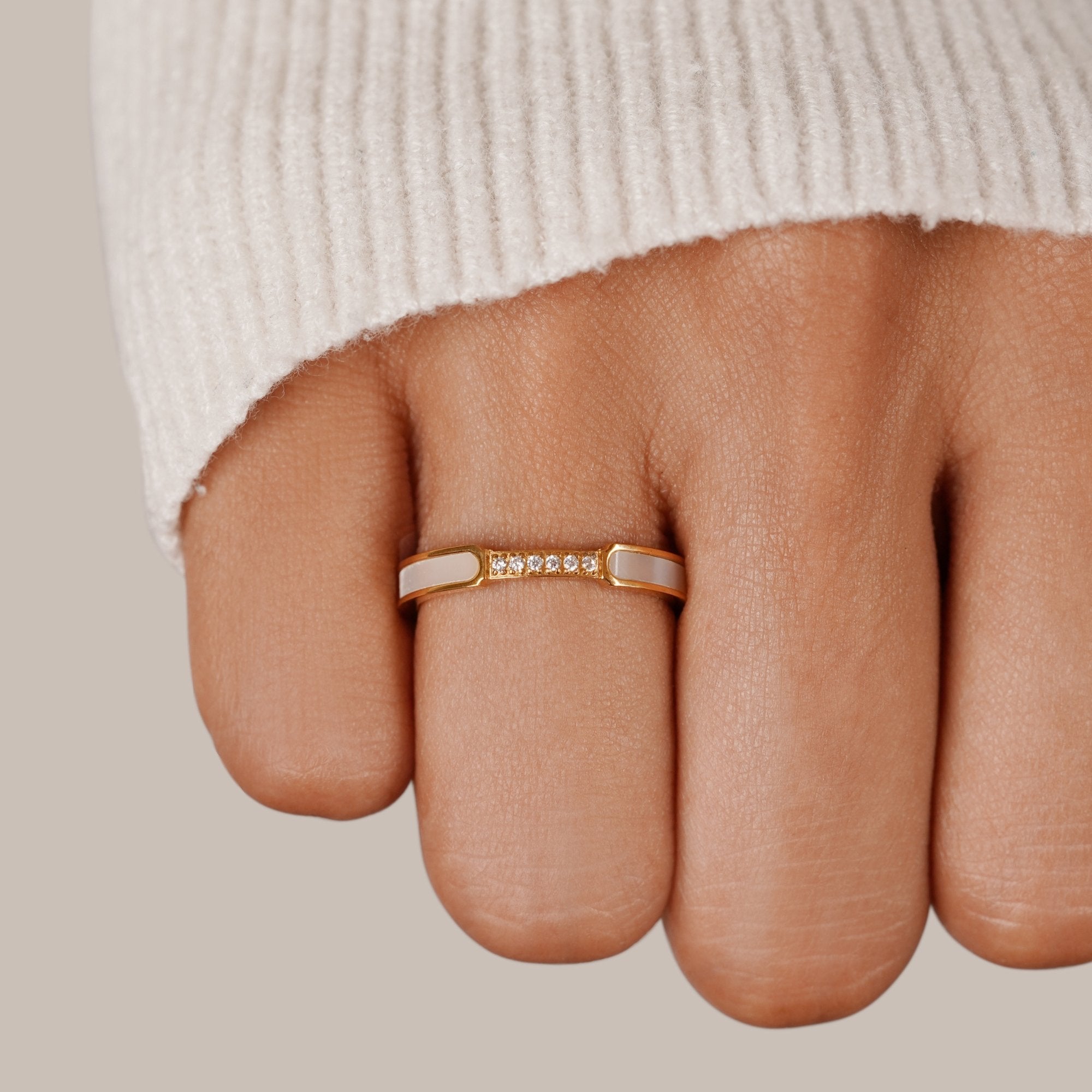 Mother Of Pearl & Crystal Ring, worn on a finger with a cream knit sleeve, gold band with