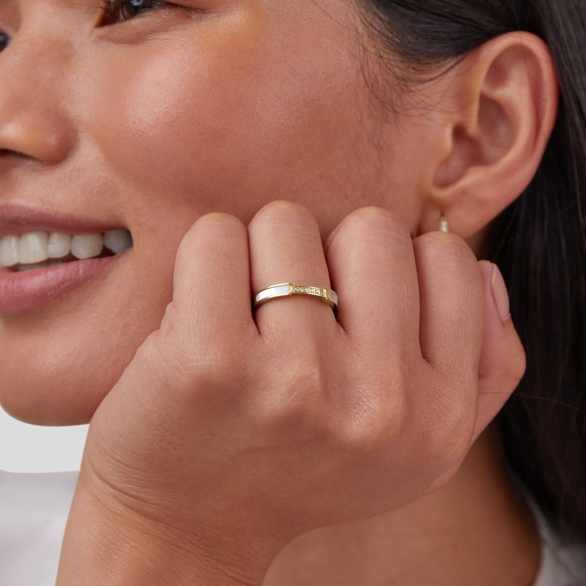 Mother Of Pearl & Crystal Ring, worn on a finger, hand resting against a smiling cheek