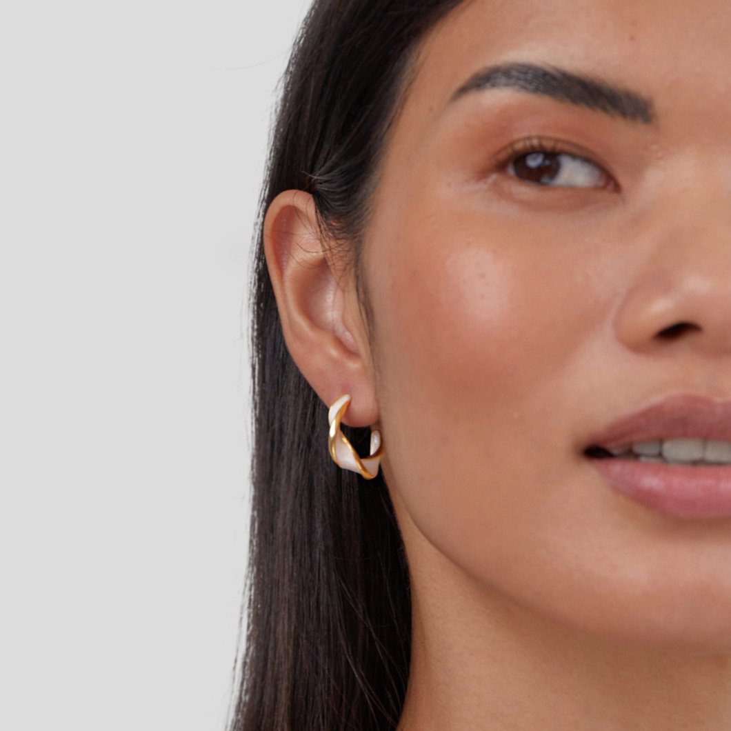 Mother of Pearl Twist Hoop Earrings, worn on an ear with a pearly white and gold twisted hoop