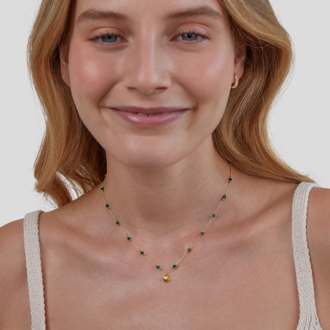 Nerissa Gold Shell & Green Bead Necklace, worn on a smiling model with a gold hoop earring
