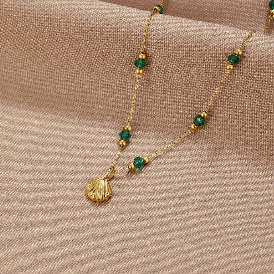 Nerissa Gold Shell & Green Bead Necklace, laid on beige fabric, gold shell pendant with green