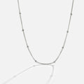 Niyah Bead Silver Chain Necklace, laid out on a light grey surface, silver chain with evenly