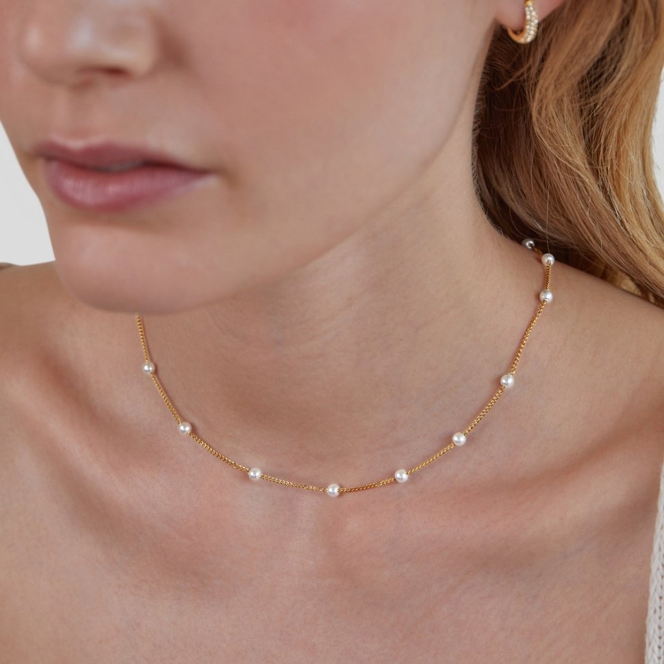 Nura Pearl 18K Gold Necklace, worn on a neck with a gold hoop earring and pearls