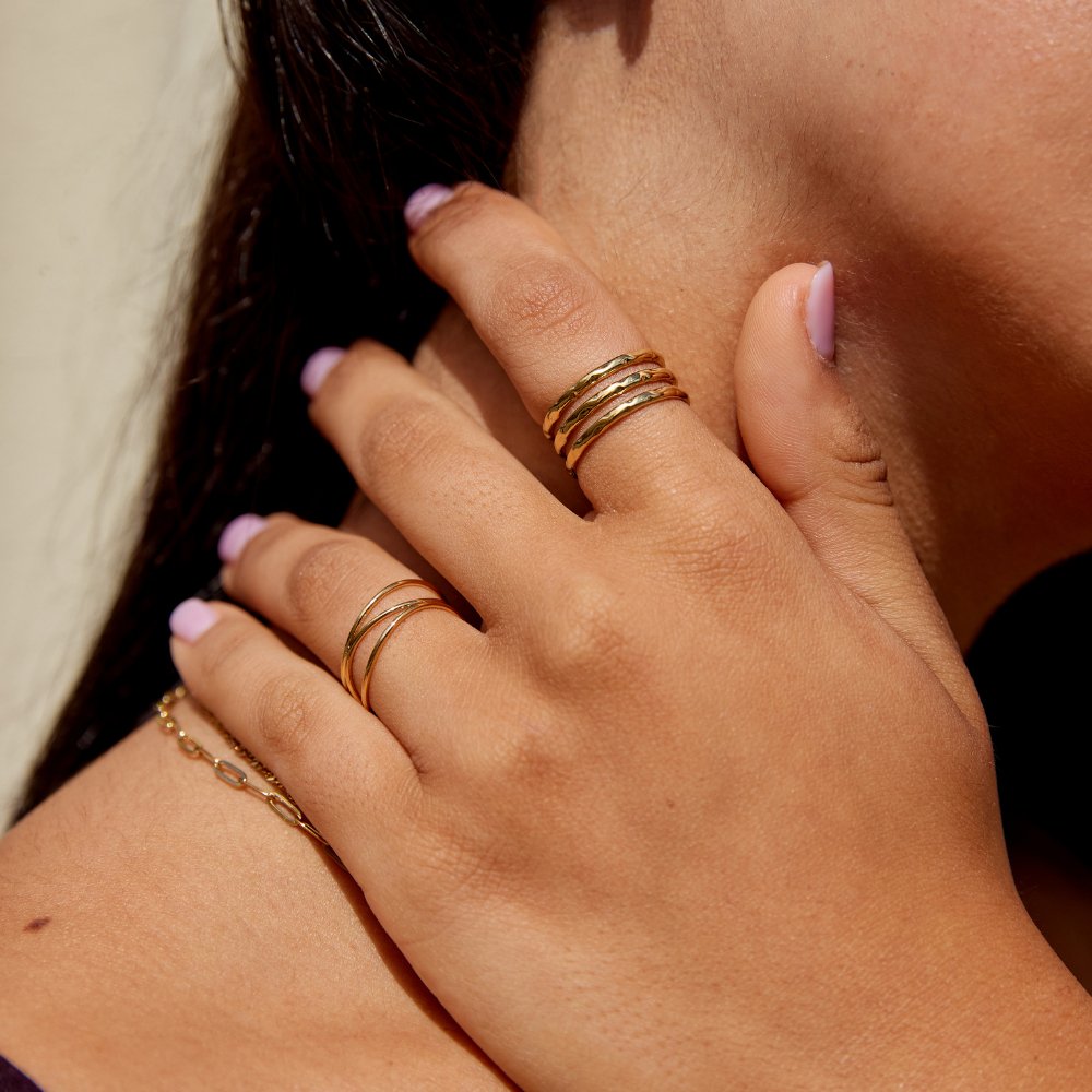 Ohio Layered Gold Ring, worn on a hand touching the neck, stacked gold bands on the index finger