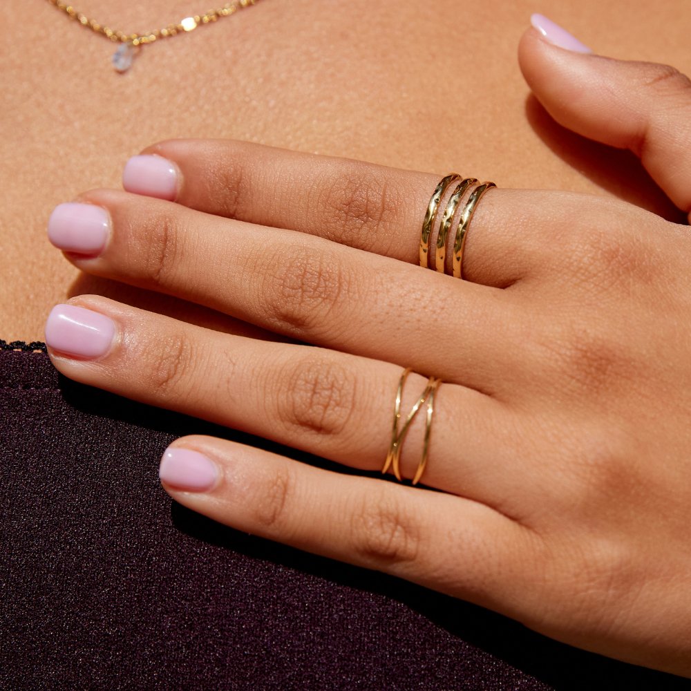 Ohio Layered Gold Ring, worn on a hand with pale pink nails, close-up of gold rings