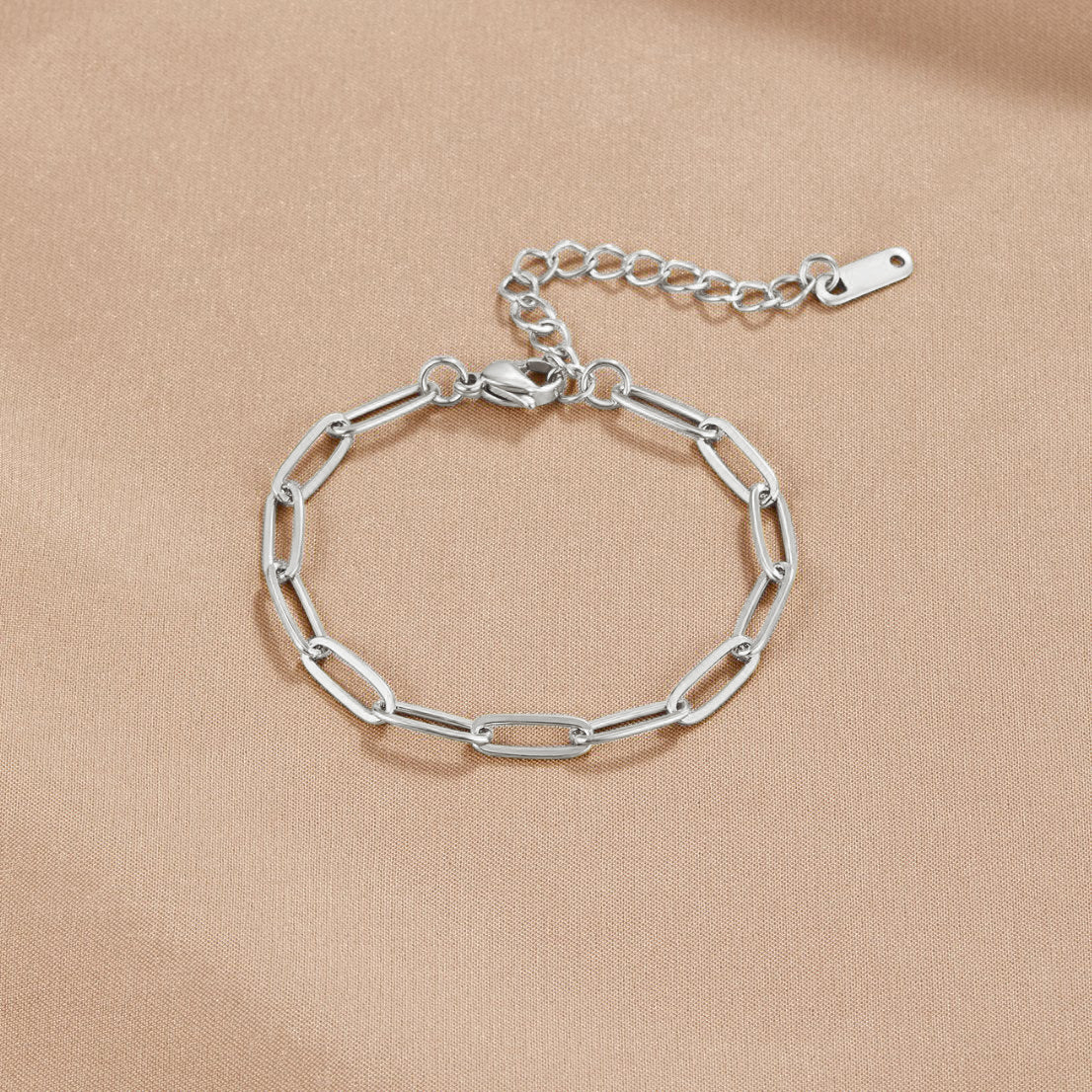 Paperclip Silver Bracelet, flat lay on beige fabric, silver paperclip chain with extender tail
