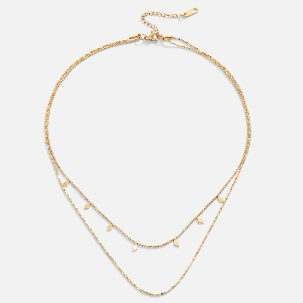 Phoenix Layered Necklace, two gold chains laid flat, with small diamond-shaped charms on the upper layer